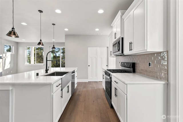 kitchen featuring sink, appliances with stainless steel finishes, a kitchen island with sink, hanging light fixtures, and white cabinetry