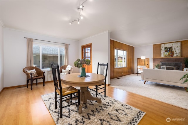 dining space featuring light wood-type flooring, a wealth of natural light, and ornamental molding