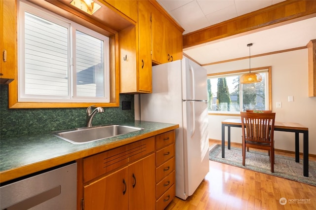 kitchen featuring tasteful backsplash, sink, decorative light fixtures, white fridge, and light hardwood / wood-style floors