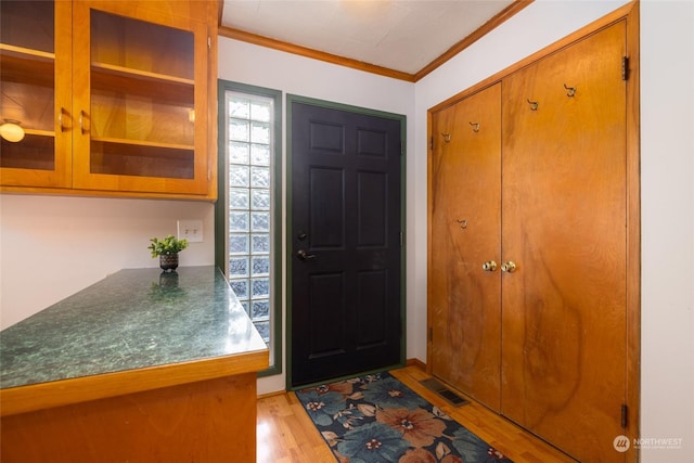 foyer entrance with light hardwood / wood-style floors and crown molding