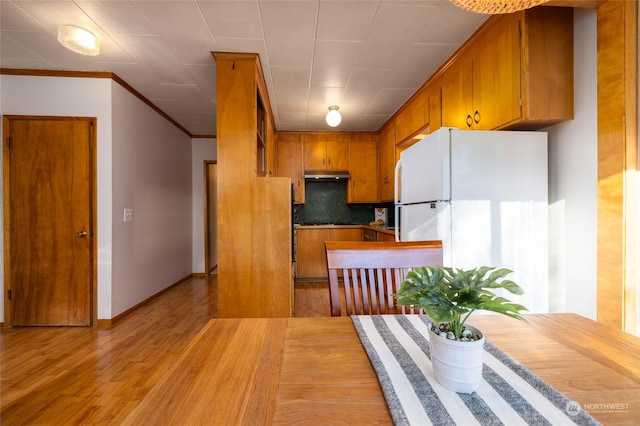 kitchen featuring decorative backsplash, light hardwood / wood-style flooring, white fridge, and ornamental molding