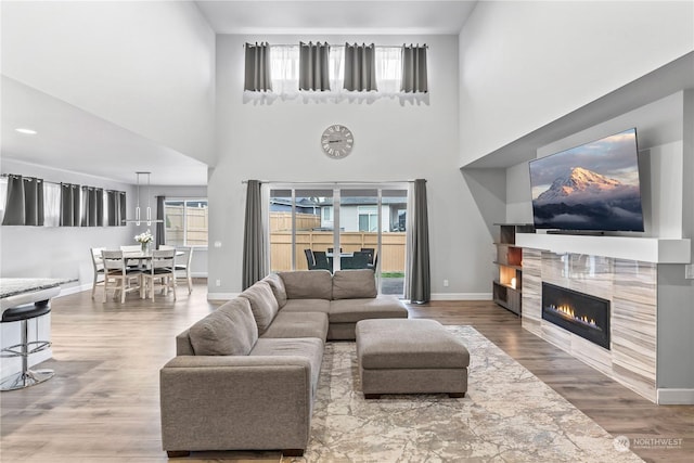 living room featuring wood-type flooring, a towering ceiling, and a fireplace