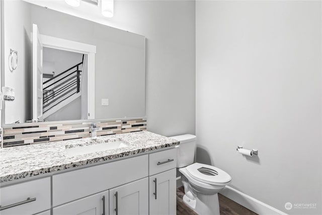 bathroom with tasteful backsplash, vanity, toilet, and hardwood / wood-style flooring