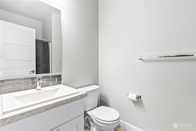 bathroom featuring vanity, decorative backsplash, and toilet