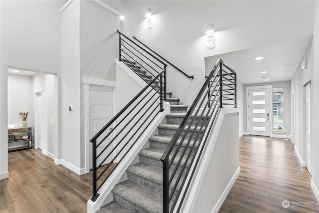 stairs featuring hardwood / wood-style flooring and a towering ceiling