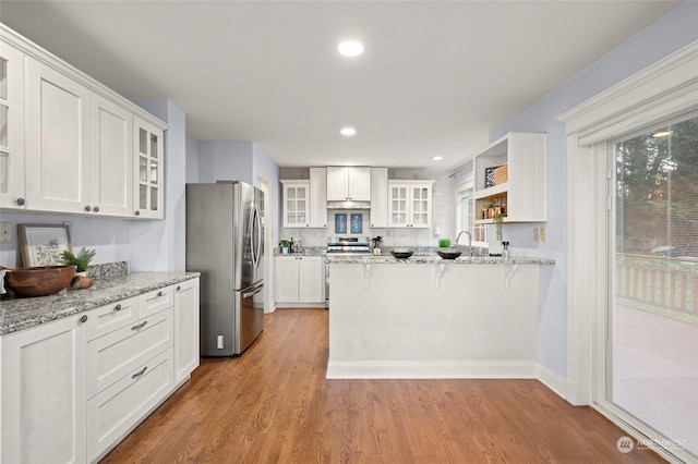 kitchen with appliances with stainless steel finishes, white cabinetry, and light stone countertops