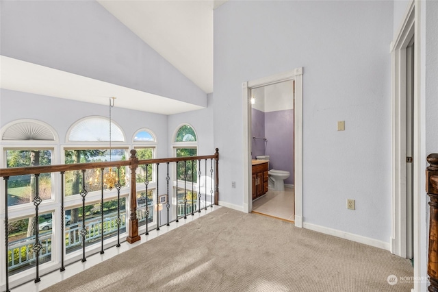 corridor featuring high vaulted ceiling and light colored carpet