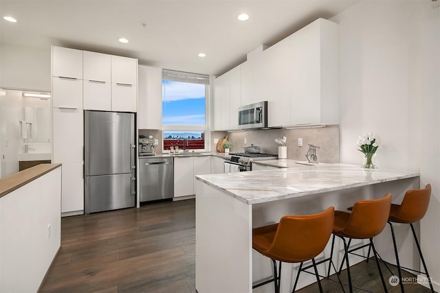 kitchen with stainless steel appliances, a kitchen breakfast bar, kitchen peninsula, and white cabinets