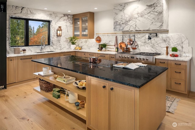 kitchen featuring light wood-type flooring, a kitchen island with sink, dark stone countertops, and sink