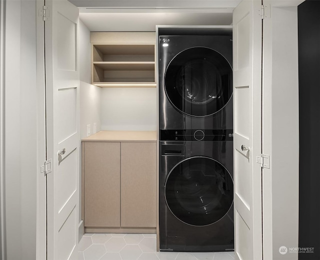 laundry room featuring stacked washing maching and dryer and light tile patterned floors