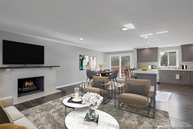 living room featuring dark hardwood / wood-style flooring, sink, and a brick fireplace