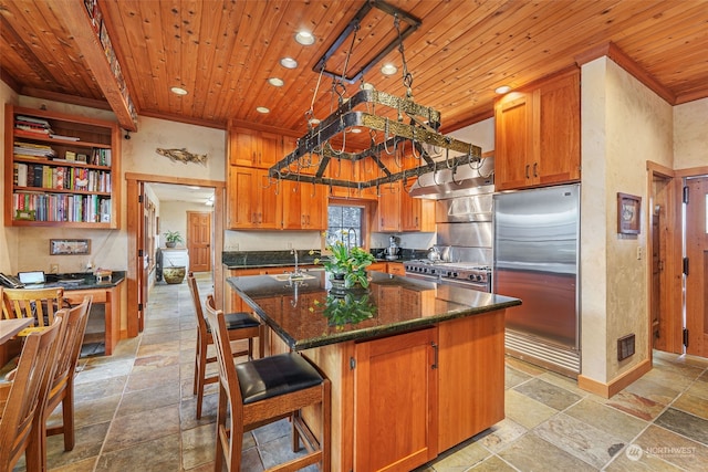 kitchen with track lighting, a center island with sink, wooden ceiling, and built in refrigerator