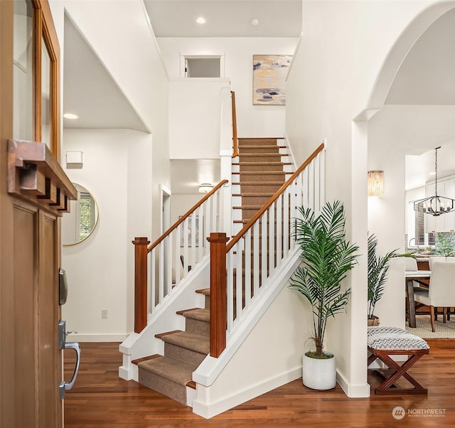 staircase with an inviting chandelier and hardwood / wood-style flooring