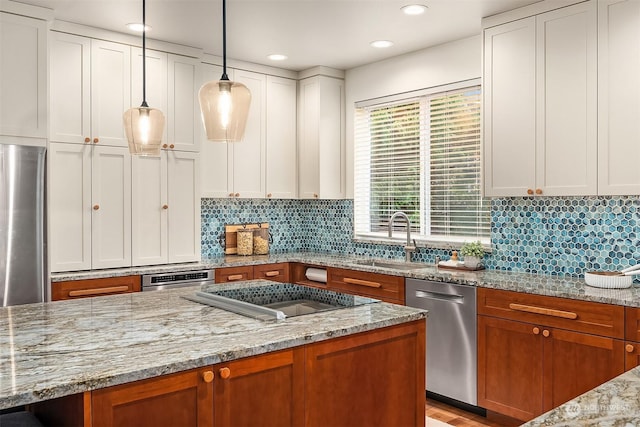 kitchen featuring light stone countertops, stainless steel appliances, sink, decorative light fixtures, and white cabinetry