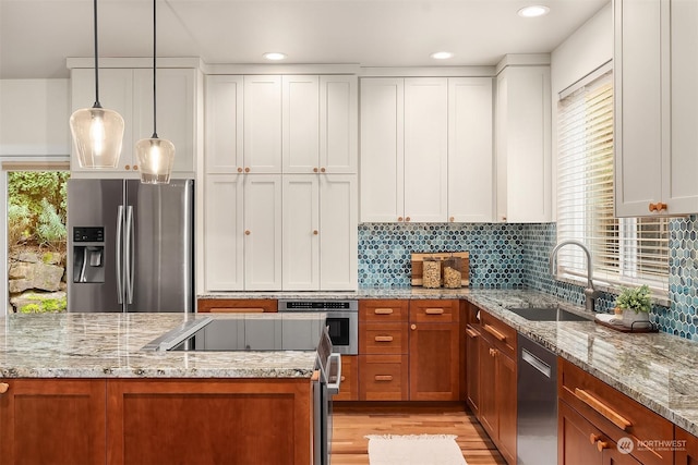 kitchen with sink, white cabinets, hanging light fixtures, and appliances with stainless steel finishes