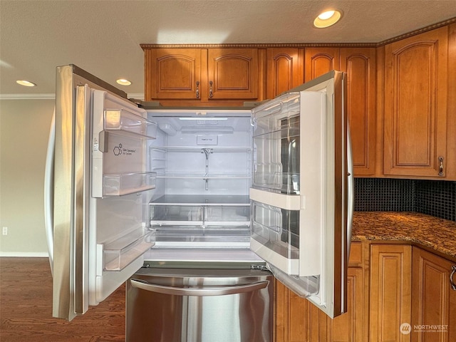 kitchen with dark hardwood / wood-style floors, dark stone countertops, backsplash, fridge, and crown molding