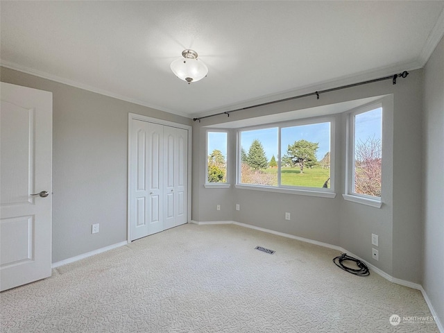 unfurnished bedroom featuring light carpet, crown molding, and a closet