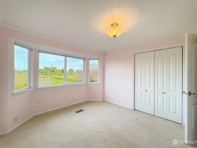 unfurnished bedroom with light colored carpet, ornamental molding, and a closet