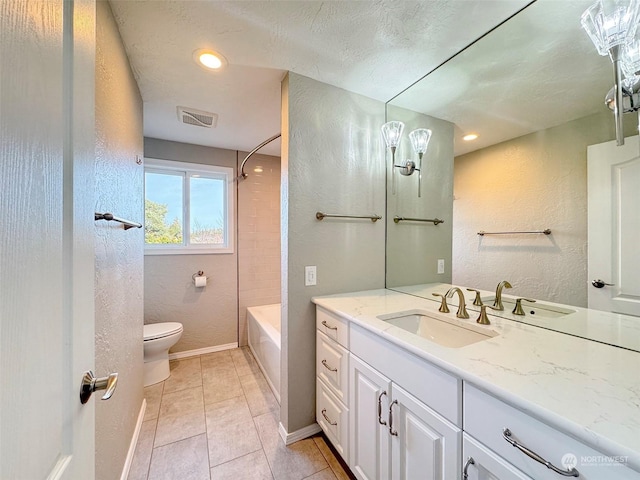 full bathroom with tiled shower / bath combo, vanity, tile patterned flooring, toilet, and a textured ceiling