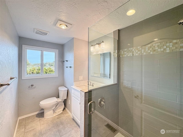 bathroom with vanity, toilet, a shower with shower door, and a textured ceiling