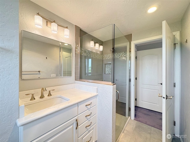 bathroom featuring tile patterned floors, vanity, an enclosed shower, and a textured ceiling