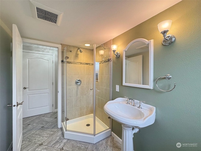 bathroom featuring a textured ceiling and a shower with shower door