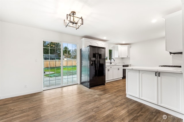 kitchen with dishwashing machine, white cabinetry, black fridge, and sink