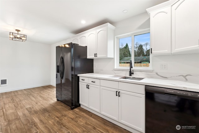 kitchen with light stone countertops, sink, white cabinetry, and black appliances