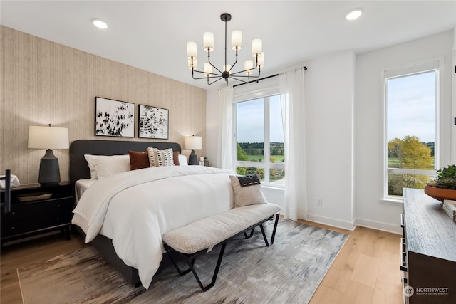 bedroom featuring multiple windows, light hardwood / wood-style flooring, and an inviting chandelier