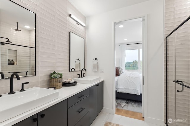 bathroom with tile patterned floors, vanity, a shower with door, and backsplash