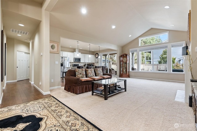 carpeted living room with sink and high vaulted ceiling