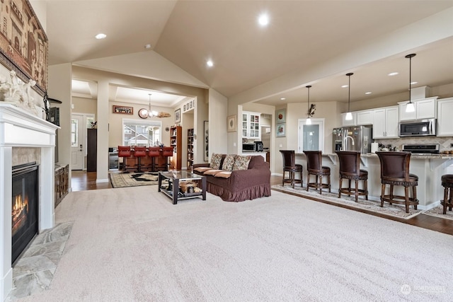 living room with a fireplace, dark carpet, a chandelier, and vaulted ceiling