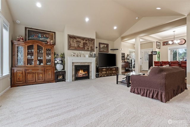 living room with carpet flooring, a tile fireplace, lofted ceiling, and a notable chandelier