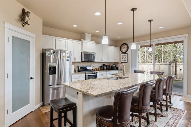 kitchen with hanging light fixtures, sink, white cabinets, and stainless steel appliances