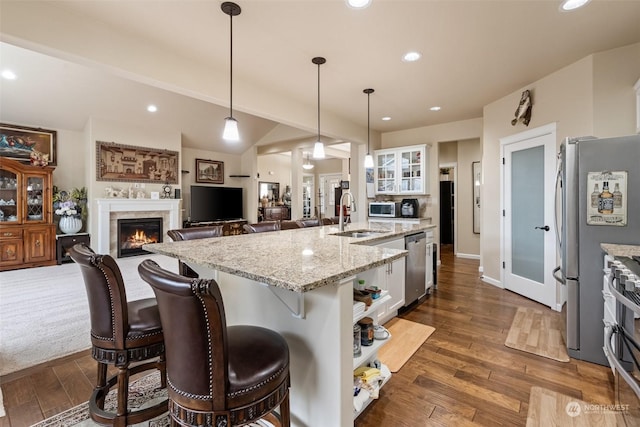 kitchen with white cabinets, sink, an island with sink, decorative light fixtures, and stainless steel appliances