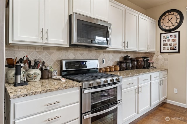 kitchen featuring light stone countertops, tasteful backsplash, stainless steel appliances, light hardwood / wood-style flooring, and white cabinets