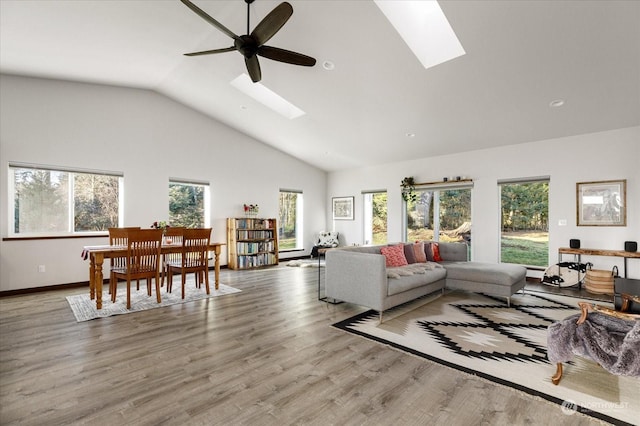 living room featuring a skylight, baseboard heating, ceiling fan, high vaulted ceiling, and light hardwood / wood-style floors