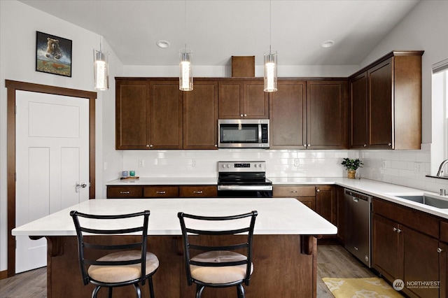 kitchen with hanging light fixtures, a center island, stainless steel appliances, and a breakfast bar area