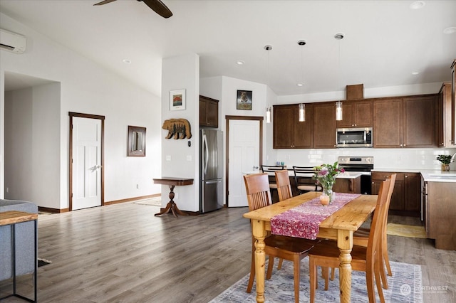 dining space with a wall mounted air conditioner, wood-type flooring, vaulted ceiling, and ceiling fan