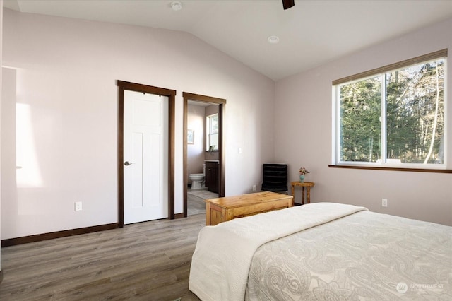 bedroom with hardwood / wood-style floors, connected bathroom, vaulted ceiling, and ceiling fan