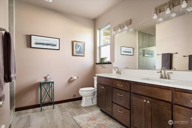 bathroom featuring a shower with door, vanity, and toilet