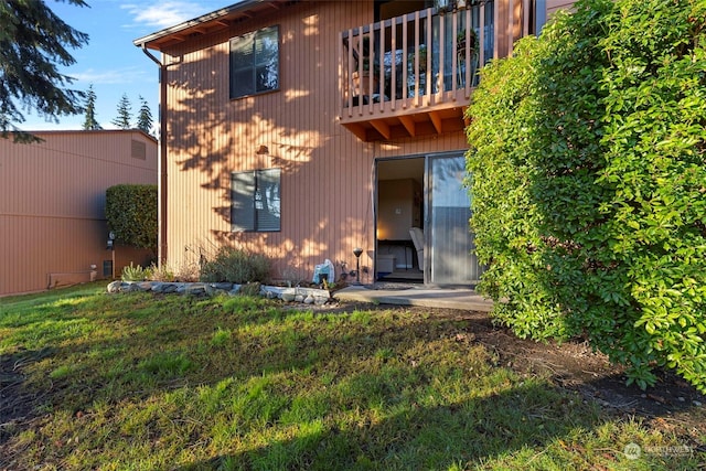 back of house featuring a balcony and a yard