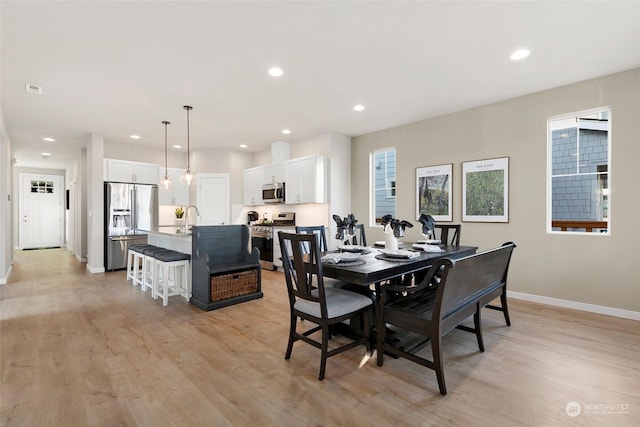 dining space with sink and light hardwood / wood-style flooring