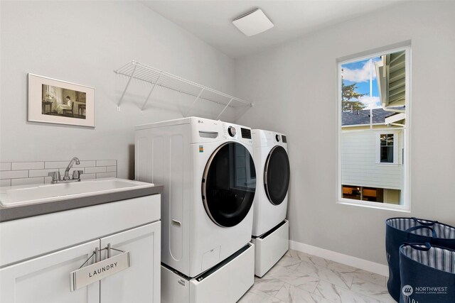 laundry room featuring washing machine and dryer, sink, and cabinets