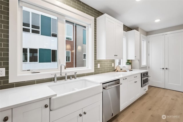 kitchen featuring decorative backsplash, stainless steel appliances, sink, light hardwood / wood-style flooring, and white cabinetry