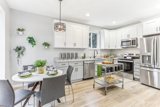 kitchen with pendant lighting, white cabinets, sink, and appliances with stainless steel finishes