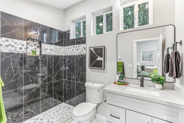 bathroom featuring a tile shower, vanity, and toilet