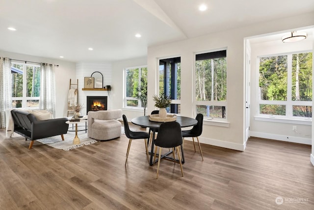 dining space with a fireplace, wood-type flooring, and lofted ceiling