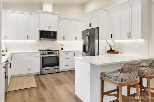 kitchen with lofted ceiling, backsplash, a breakfast bar area, white cabinetry, and stainless steel appliances