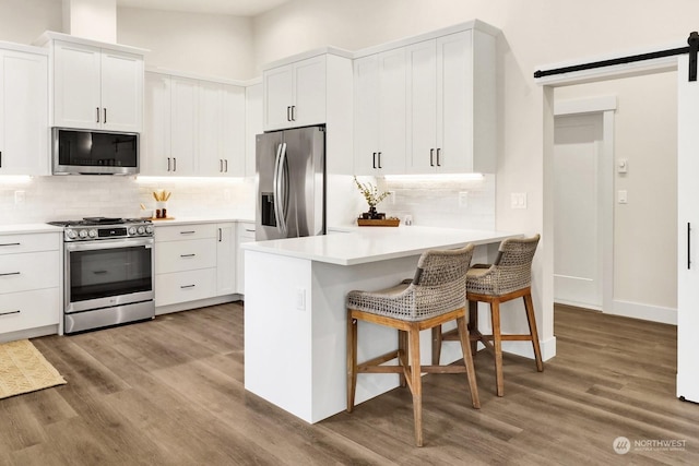 kitchen with a breakfast bar, light wood-type flooring, white cabinetry, and stainless steel appliances